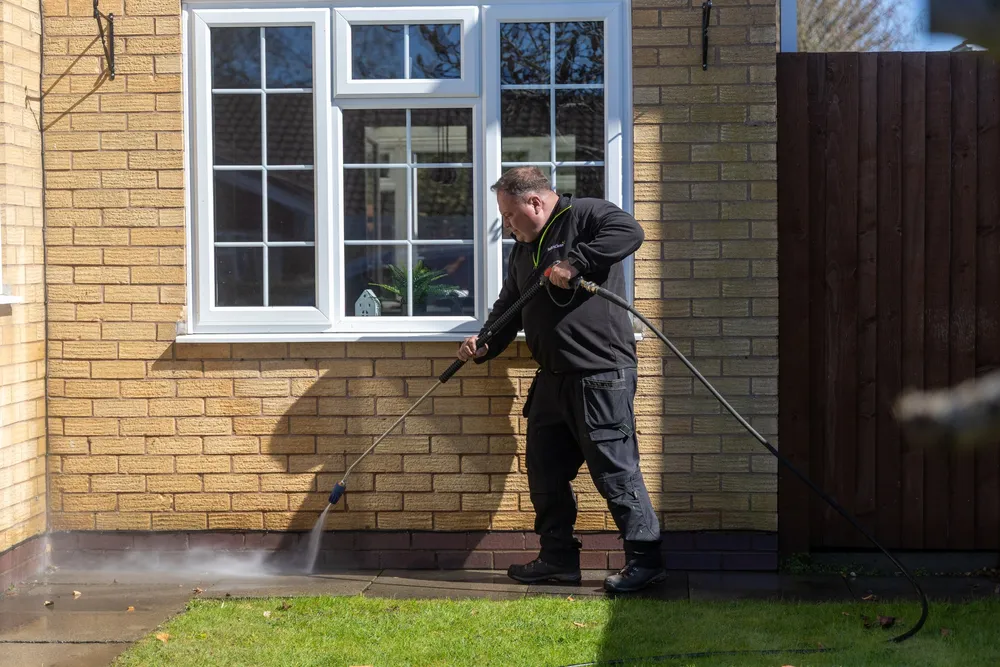 Operative pressure washing a paved area beside a bay window