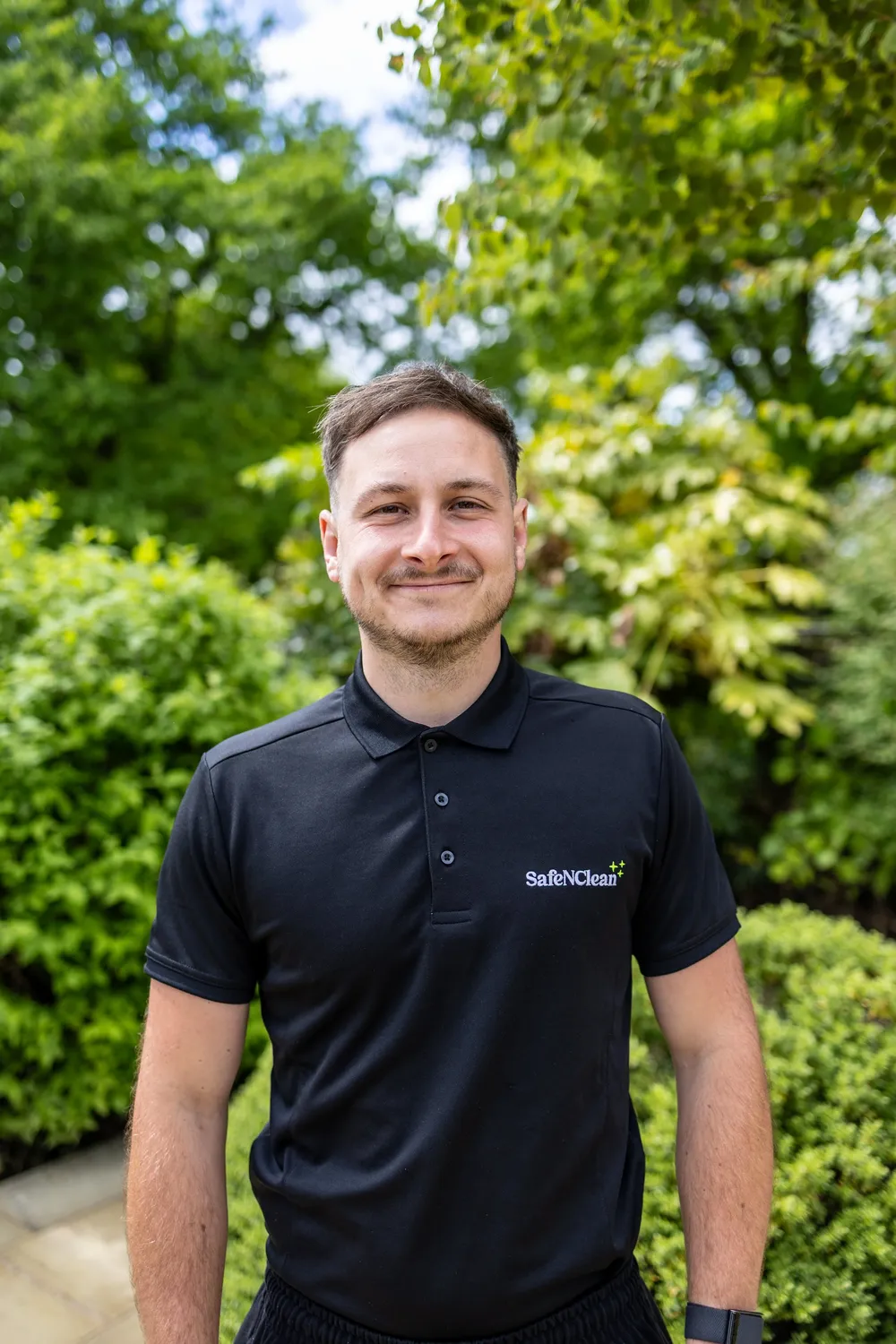 Member of the Safe'N'Clean team standing in front of greenery